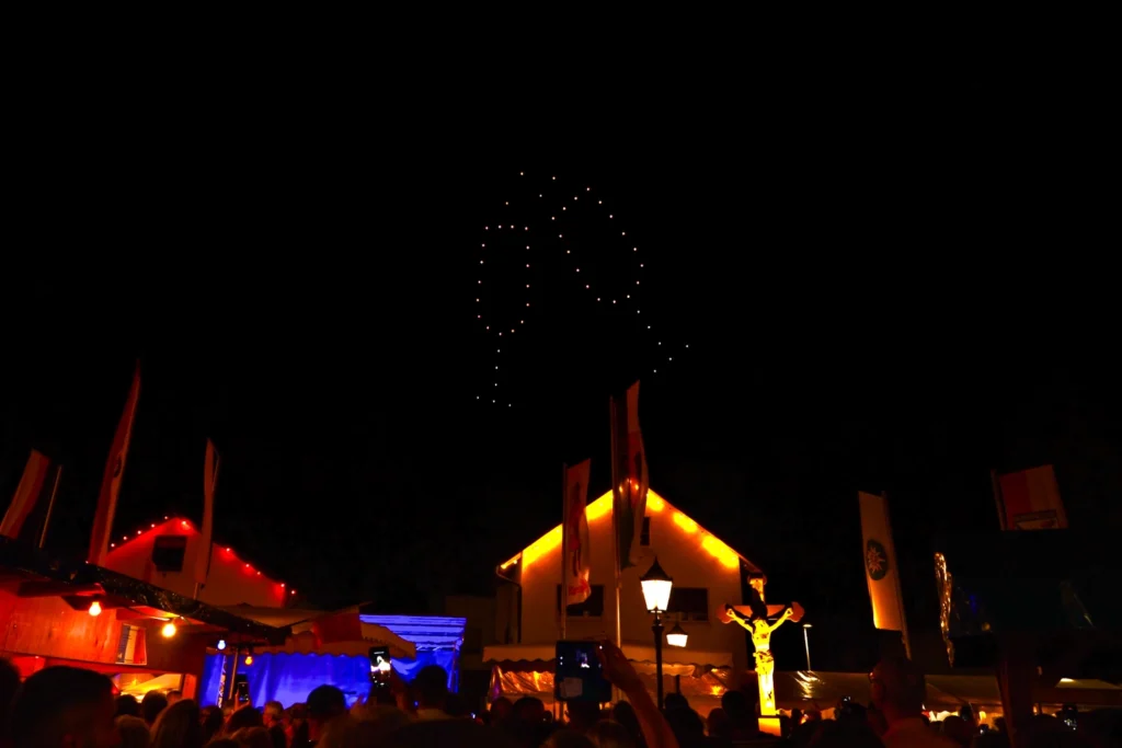 Zwei anstoßende Sektgläser aus leuchtenden Show-Drohnen am Nachthimmel beim Kartunger Straßenfest 2026